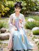 A woman in a blue and pink hanbok is posing for a picture.