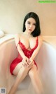 A woman in a red lingerie sitting in a bathtub.