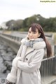 A woman in a gray coat and scarf posing for a picture.