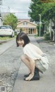 A woman crouching down on the side of a road.