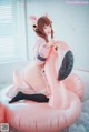 A woman in a pink outfit is sitting on an inflatable flamingo.