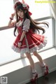 A woman in a red and white dress posing by a window.