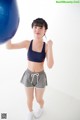 A woman in a sports bra top and shorts holding a blue ball.