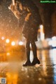 A woman standing in the rain holding an umbrella.