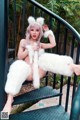 A woman in a white fur coat sitting on a set of stairs.