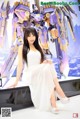 A woman in a white dress posing in front of a giant robot.